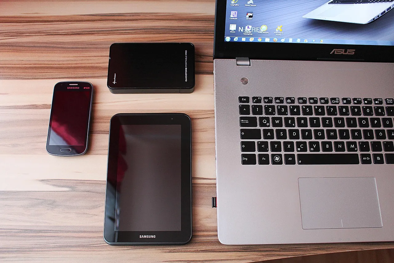 Laptop, Tablet, Smartphone und externe Festplatte auf einem Holztisch